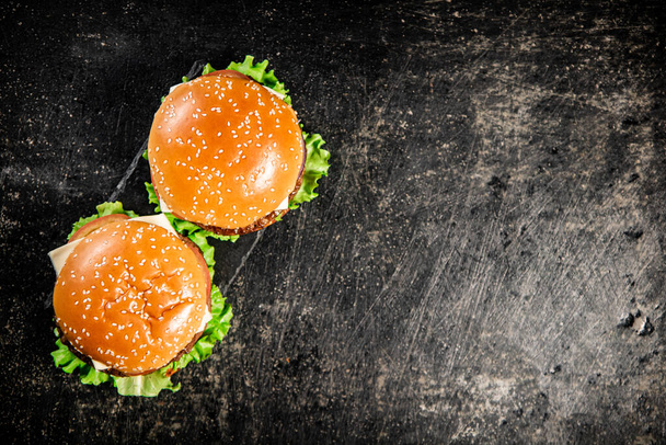 A burger on a stone board on a table. On a black background. High quality photo - Photo, Image