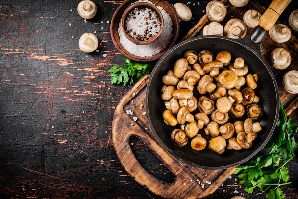 Frying pan with fried small mushrooms with parsley. Against a dark background. High quality photo - Fotoğraf, Görsel