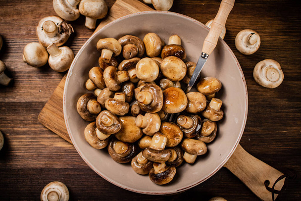 Fried mushrooms in a bowl on a cutting board. On a wooden background. High quality photo - Foto, afbeelding