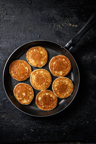 Homemade pancakes in a frying pan. On a black background. High quality photo - Фото, зображення