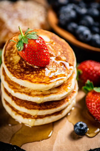 A pile of pancakes with berries and honey. On a black background. High quality photo - Foto, imagen