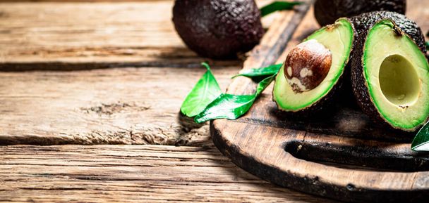 Halves of fresh avocado on a cutting board. On a wooden background. High quality photo - Foto, afbeelding