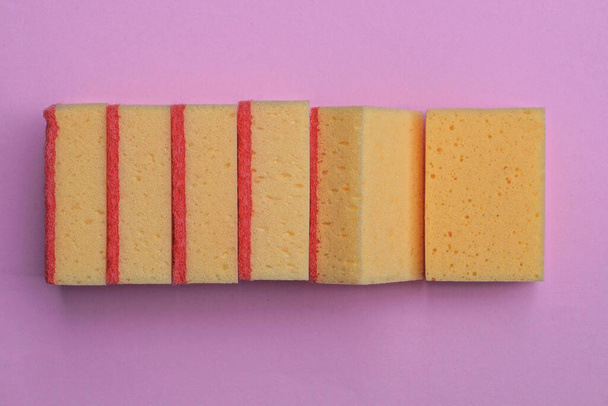 a row of red yellow foam rubber washcloths lie on a pink table - Photo, Image