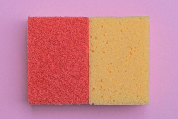 two yellow and red foam sponges lie on a pink table - Fotoğraf, Görsel