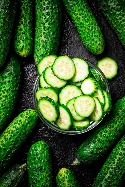 Sliced and whole cucumbers on the table. Against a dark background. High quality photo - Valokuva, kuva