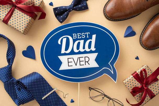 Lovely Father's Day tribute idea. Overhead shot of greeting plaque, hearts, shoes, necktie, bow-tie, spectacles, and gift boxes with burgundy ribbon bows on a neutral backdrop - Photo, Image