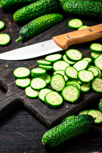 Cucumbers cut on a cutting board. On a black background. High quality photo - Foto, imagen