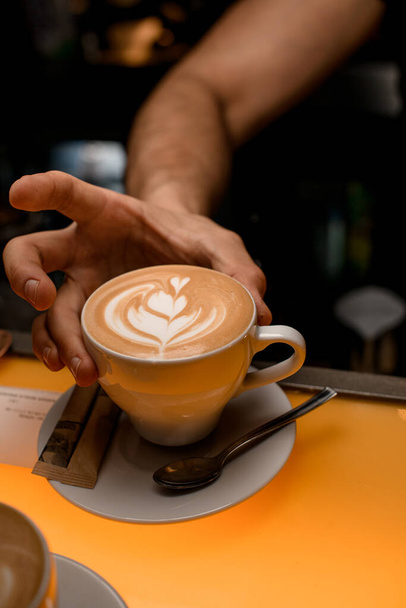 Barman hands holding fresh coffee or latte art in white cup at restaurant, bar or pub - Fotó, kép