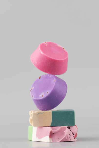 Natural handmade soap. Bright pieces of soap balance in the shape of a pyramid on a grey background. - Valokuva, kuva