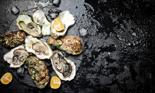 Raw oysters on a stone board. On a black background. High quality photo - Foto, afbeelding