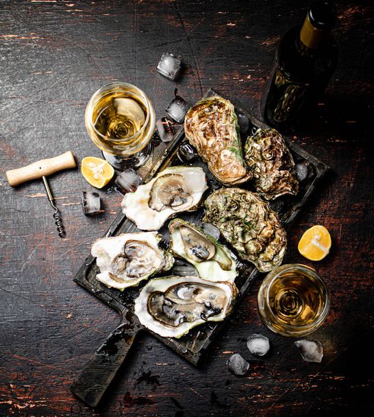Raw oysters with ice on an cutting board. On a rustic dark background. High quality photo - Fotoğraf, Görsel