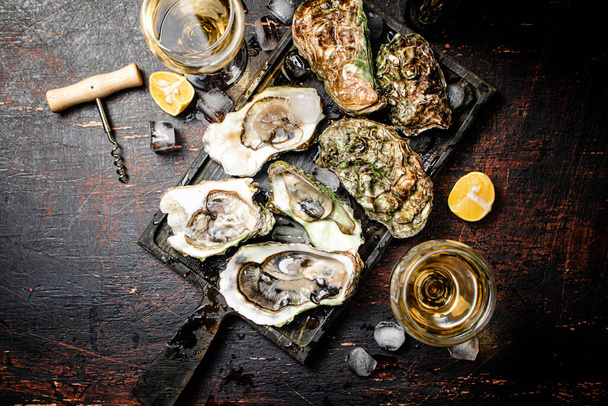 Raw oysters with ice on an cutting board. On a rustic dark background. High quality photo - Foto, Imagen