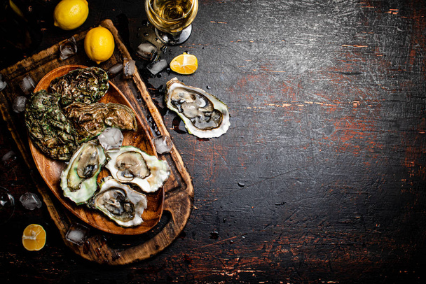 Fresh oysters with ice on a wooden plate. Against a dark background. High quality photo - Foto, Imagem