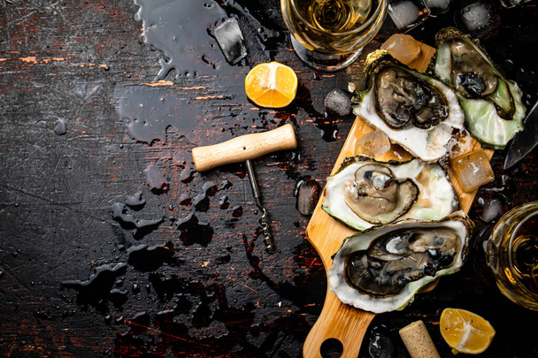 Oysters on a wooden cutting board. On a rustic dark damp background. High quality photo - Fotoğraf, Görsel