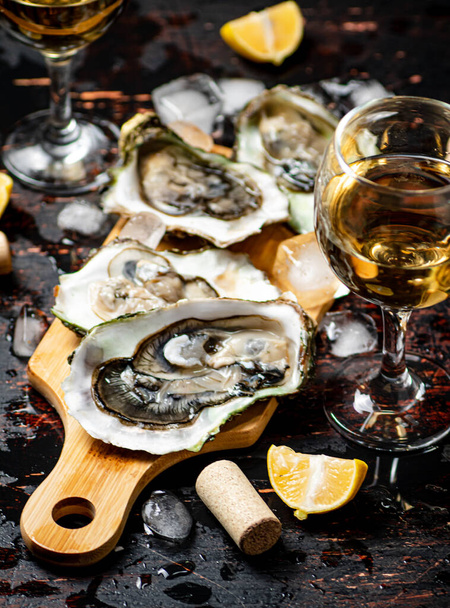 Oysters on a wooden cutting board. On a rustic dark damp background. High quality photo - Fotó, kép