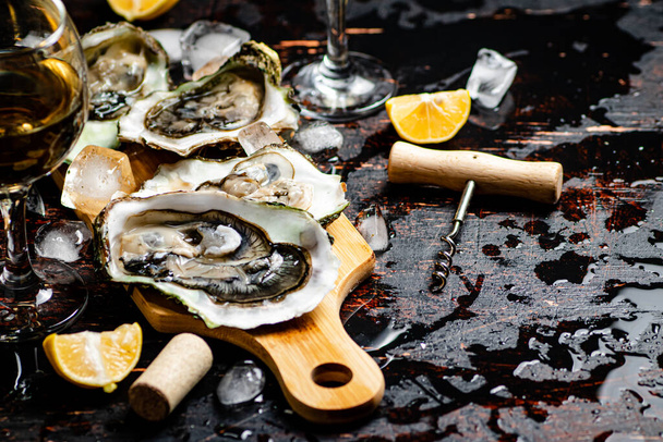 Oysters on a wooden cutting board. On a rustic dark damp background. High quality photo - Фото, изображение