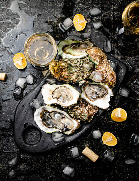 Fresh oysters on a cutting board. On a black background. High quality photo - Fotó, kép