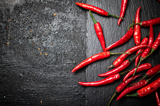 Chili pepper pods on a stone board. On a black background. High quality photo - 写真・画像