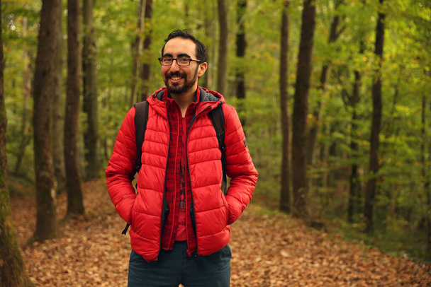 Trekking lover, adventurer bearded Caucasian man posing in front of a green blurry background in the forest - Foto, imagen