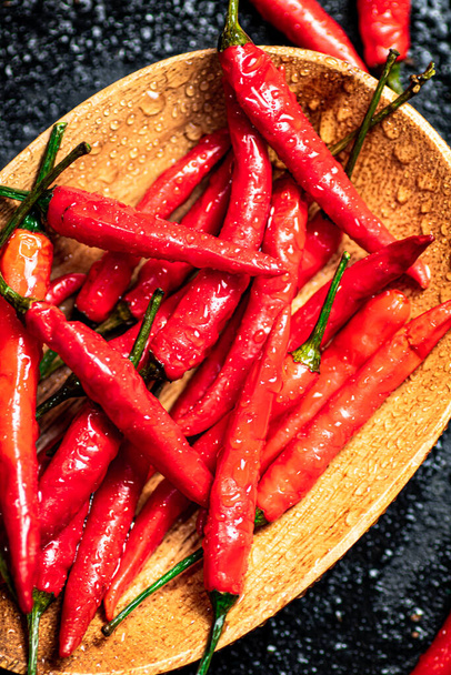 Chili peppers on a wooden plate. On a black background. High quality photo - 写真・画像