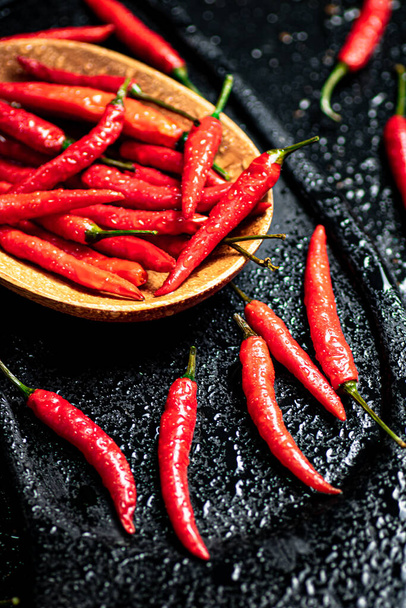Pods of hot chili peppers on a cutting board. On a black background. High quality photo - 写真・画像