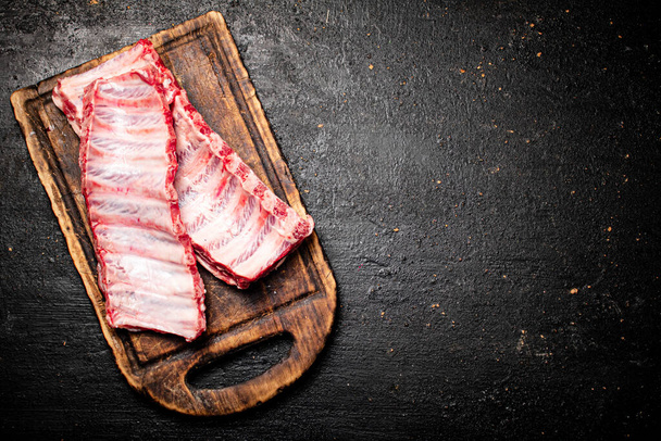 Raw ribs on a cutting board. On a black background. High quality photo - Foto, imagen