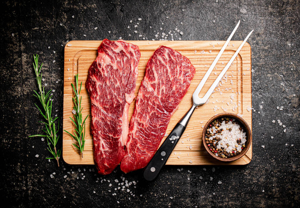 Raw steak on a wooden cutting board. On a black background. High quality photo - Fotó, kép