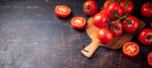 Fresh tomatoes on a wooden cutting board. Against a dark background. High quality photo - Фото, зображення