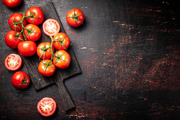 Fresh tomatoes on a wooden cutting board. Against a dark background. High quality photo - Foto, Bild