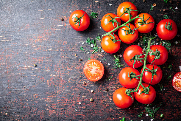Tomatoes on a branch with pieces of greens and spices. Against a dark background. High quality photo - Valokuva, kuva