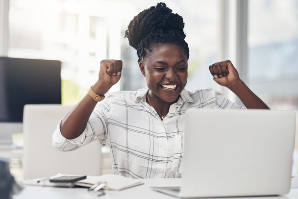 Zwarte vrouw, succes en laptop te vieren zakelijke winst, winst of prestatie in het kantoor. Afrikaanse vrouwelijke ondernemer aan een bureau met motivatie, vuist en technologie voor bonus, overwinning en promotie. - Foto, afbeelding