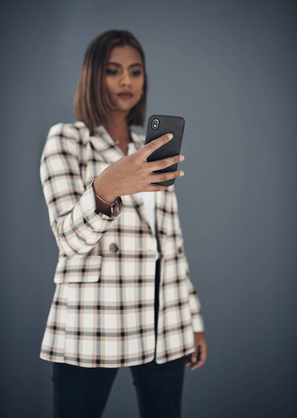 Young business woman, selfie and fashion by wall background with pride, career or creativity on social media app. Indian businesswoman, photography and influencer with profile picture, post or blog. - Photo, image