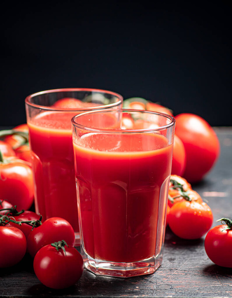 Glasses of tomato juice on the table. On a black background. High quality photo - Фото, зображення