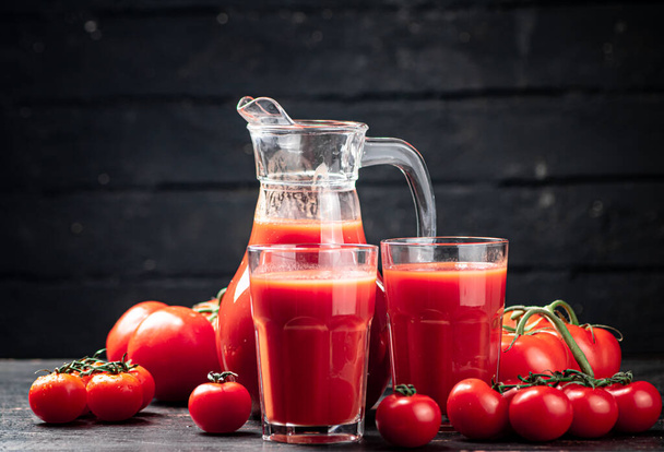Fresh tomato juice in a jug. On a wooden background. High quality photo - Photo, Image