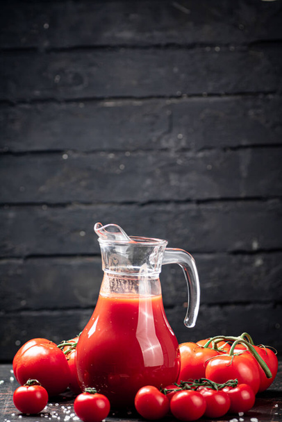 Juice from ripe tomatoes on the table. On a black wooden background. High quality photo - Fotó, kép