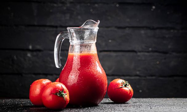 Fresh tomato juice in a jug. On a wooden background. High quality photo - Foto, Bild