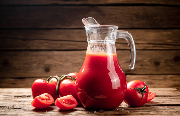 Свежий томатный сок в кувшине. На деревянном фоне. Высокое качество фото - Фото, изображение