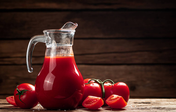 Sürahide taze domates suyu. Ahşap bir arka planda. Yüksek kalite fotoğraf - Fotoğraf, Görsel