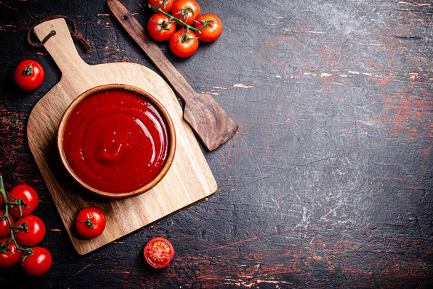 Tomato sauce on a wooden cutting board. Against a dark background. High quality photo - Фото, зображення