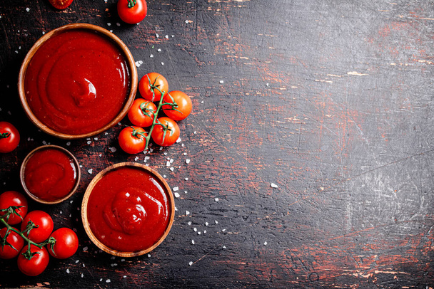 Tomato sauce in wooden plates with pieces of salt. Against a dark background. High quality photo - Foto, imagen