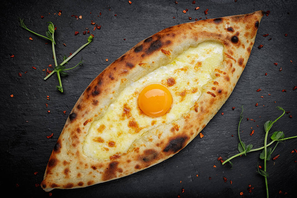 Adjaran style khachapuri with egg and cheese, a mouthwatering close-up - Фото, изображение