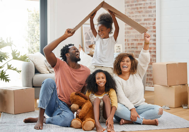 Black family, floor and cardboard roof in home living room with game, laughing and bond with love. Father, mother and daughter with play, relax of box for sign of security in family house with smile. - Фото, изображение