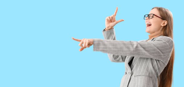 Laughing young businesswoman showing loser gesture on light blue background with space for text - Foto, afbeelding