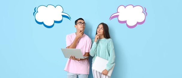 Thoughtful young couple with laptops and blank speech bubbles on light blue background - Foto, afbeelding