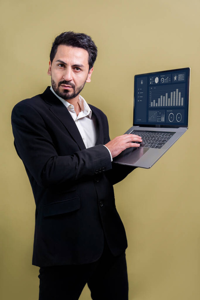 Successful businessman in black suit with innovative tech concept, standing pose and holding laptop and smiling with excitement on copyspace background for promotion or advertisement. Fervent - Foto, afbeelding