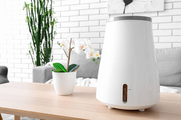 Modern humidifier and flowers in pot on table in interior of living room - Photo, Image