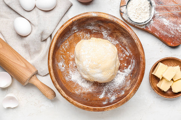Bowl with raw dough for Italian Easter bread and ingredients on white background - Фото, зображення