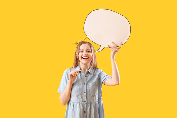 Happy young woman with blank speech bubble on yellow background - Фото, зображення