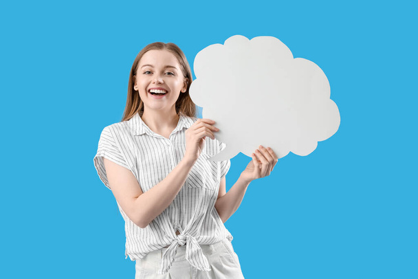 Happy young woman with blank speech bubble on blue background - Photo, Image