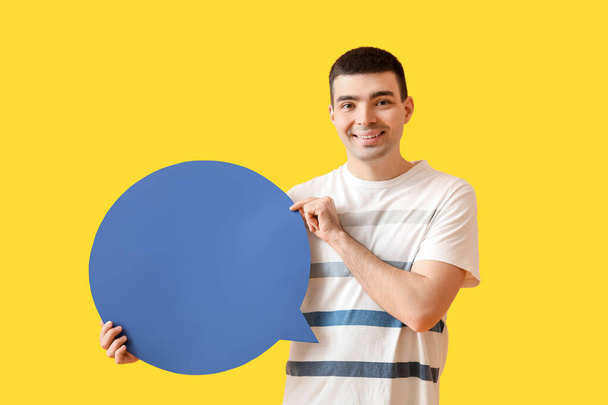 Beau jeune homme avec bulle de discours vierge sur fond jaune - Photo, image